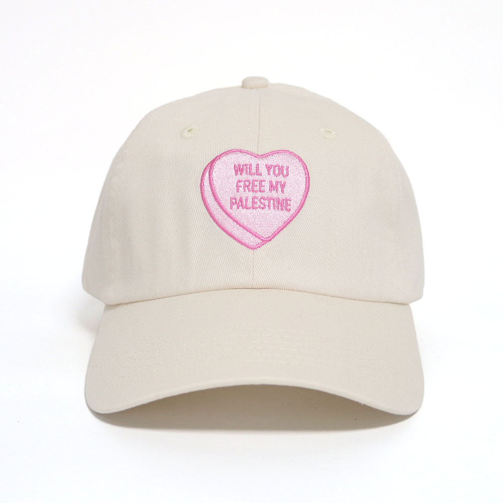 Off-white dad hat with a pink heart, similar to candy hearts, with the text 'will you free my Palestine'. 