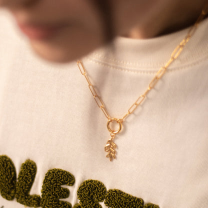 One olive branch charm on a gold paperclip chain necklace.