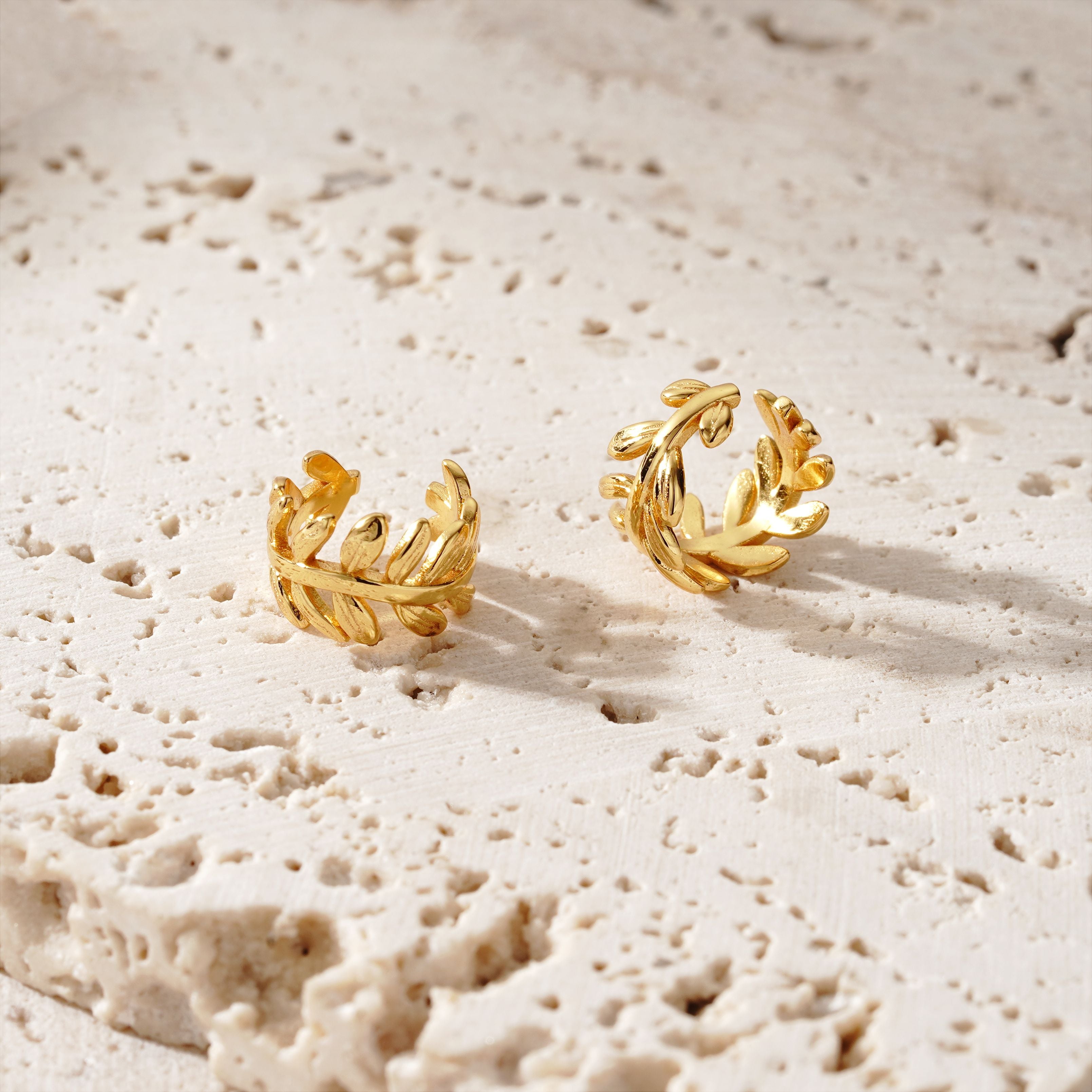 2 gold ear cuffs on a concrete surface